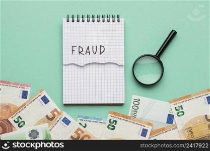 fraud word written notepad with banknotes