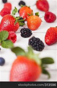 Freash organic healthy strawberries and rasppberries and blackberries on wood background