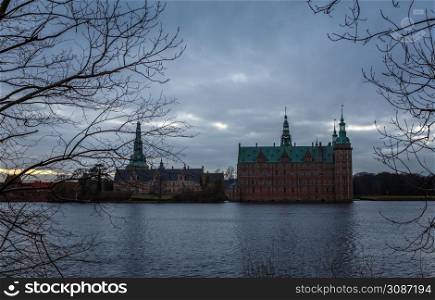 Frederiksborg castle in the evening, with lake and tree in the foreground, Hillerod, Denmark
