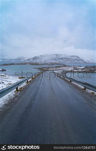 Fredvang Bridges and road in Lofoten islands, Nordland county, Norway, Europe. White snowy mountain hills and trees, nature landscape background in winter season. Famous tourist attraction.