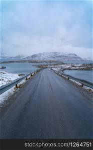 Fredvang Bridges and road in Lofoten islands, Nordland county, Norway, Europe. White snowy mountain hills and trees, nature landscape background in winter season. Famous tourist attraction.