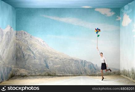 Free and careless. Beautiful young caucasian businesswoman flying on windmill