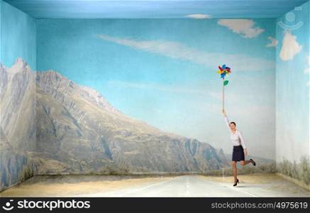 Free and careless. Beautiful young caucasian businesswoman flying on windmill