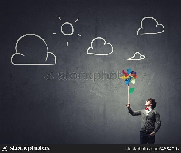 Free and careless. Young happy businessman with colorful windmill in hand