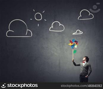 Free and careless. Young happy businessman with colorful windmill in hand
