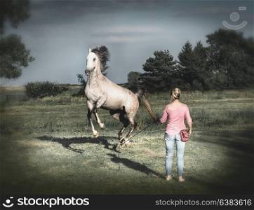 Free horse high jumping on the hind legs and playing with a woman. Horsemanship scene . Horse free dressage