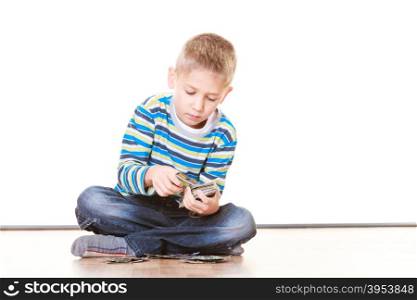 Free time, fun and hobby. Little boy play indoors sit on floor and play collect cards.