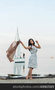 Free woman enjoying freedom feeling happy at beach at morning. Beautiful serene woman and welcoming yacht and sailor with arms opened outstretched up. Hispanic Caucasian female model