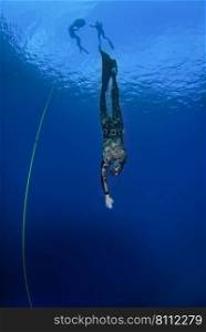 Freediver training with a line in the open sea. Freediver practising in the open blue water