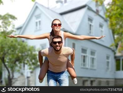 freedom and people concept - happy couple having fun in summer over living house background. happy couple having fun in summer over house
