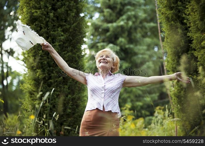 Freedom. Happy Old Lady with Hut smiling in The Garden. Lifestyle