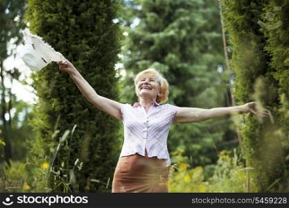 Freedom. Happy Old Lady with Hut smiling in The Garden. Lifestyle