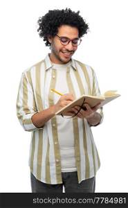 freedom, motion and happiness concept - happy smiling young man in glasses with diary and pencil writing over white background. happy smiling young man with diary and pencil