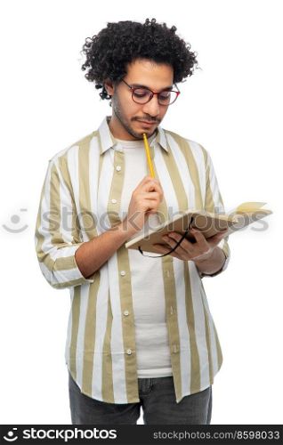 freedom, motion and happiness concept - thinking young man in glasses with diary and pencil writing over white background. thinking young man with diary and pencil