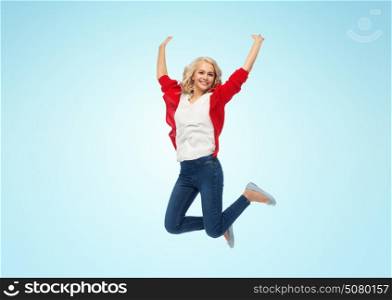 freedom, motion and people concept - smiling young woman jumping in air over blue background. smiling young woman jumping in air