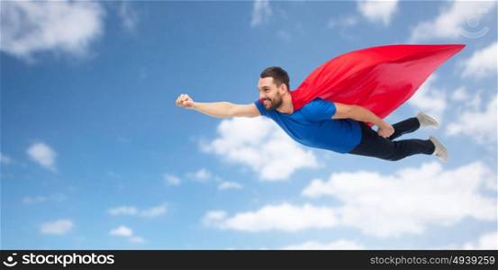 freedom, power, motion and people concept - happy man in red superhero cape flying in air over blue sky and clouds background. happy man in red superhero cape flying on air