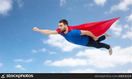 freedom, power, motion and people concept - man in red superhero cape flying over blue sky and clouds background