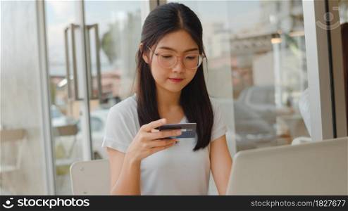 Freelance Asian women online shopping at coffee shop. Young Asia Girl using laptop, credit card buy and purchase e-commerce on internet on table at an outdoor cafe in evening concept.