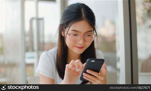 Freelance Asian women using mobile phone at a coffee shop. Young Asia Girl using smartphone checking social media internet on table at an outdoor cafe in the evening concept.