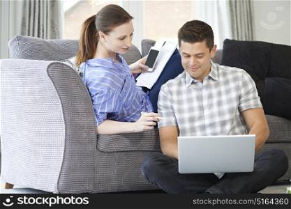 Freelance Couple Working From Home Looking At Laptop Together
