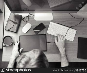 Freelance developer and designer working at home, man using desktop computer. Black and white photo