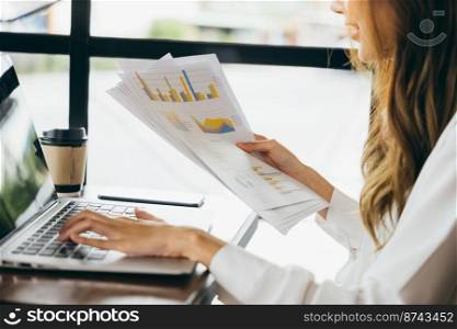 Freelance female hold paperwork documents paper graphs and using laptop at cafe, Asian young business woman working analyzing financial for budget or report graph document paper with computer