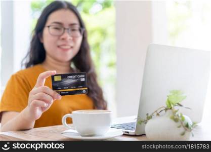 freelance people business female casual Abstract blur with focus on show holding a credit card working with laptop computer in coffee shop like the background,for online shopping and payment