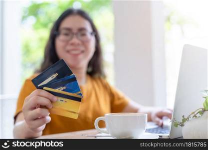 freelance people business female casual Abstract blur with focus on show holding a credit card working with laptop computer in coffee shop like the background,for online shopping and payment