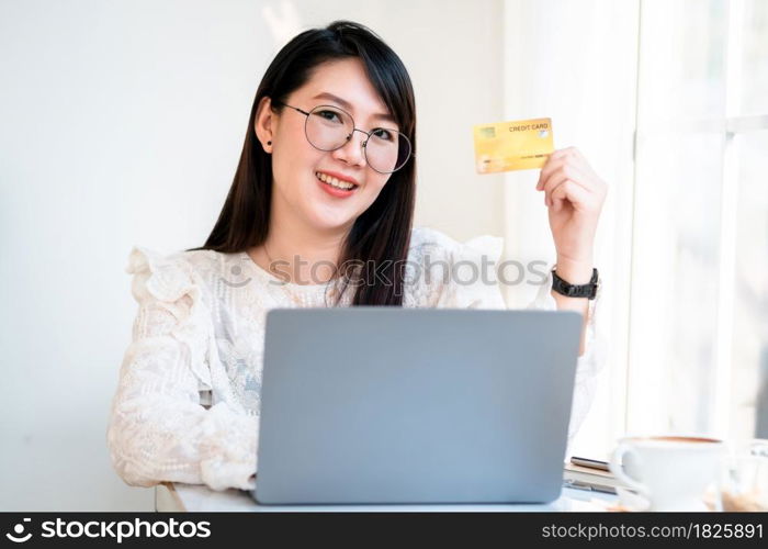 freelance people business female casual show holding a credit card working with laptop computer in coffee shop like the background,for online shopping and payment via internet.