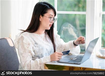 freelance people business female casual show holding a credit card working with laptop computer in coffee shop like the background,for online shopping and payment via internet.