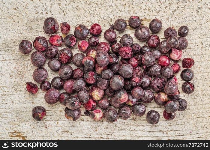 Freeze dried elderberries against rustic barn wood. Elderberries are rich in antioxidants and minerals which make them perfect in battling the common cold.