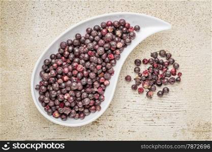 Freeze dried elderberries in a teardrop bowl against rustic barn wood. Elderberries are rich in antioxidants and minerals which make them perfect in battling the common cold.