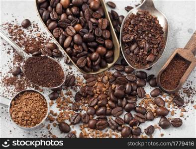 Freeze dried instant coffee granules with beans and ground coffee in various spoons and scoops on white background. Top view