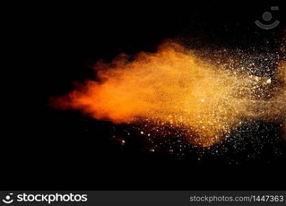 Freeze motion of orange color powder exploding on black background.