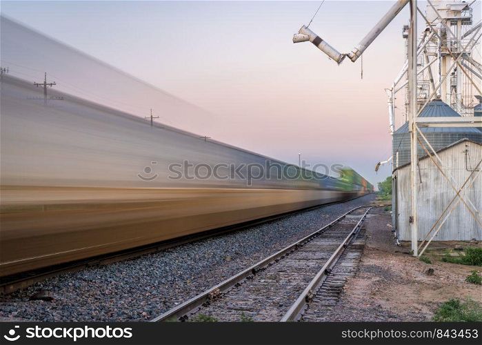 freight container train passing a rural town with grain elevator