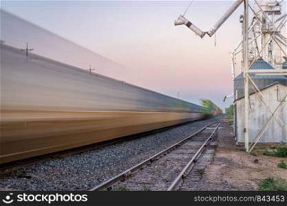 freight container train passing a rural town with grain elevator