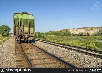 freight train with covered hopper cars to transport grain is running through Nebraska Sandhills