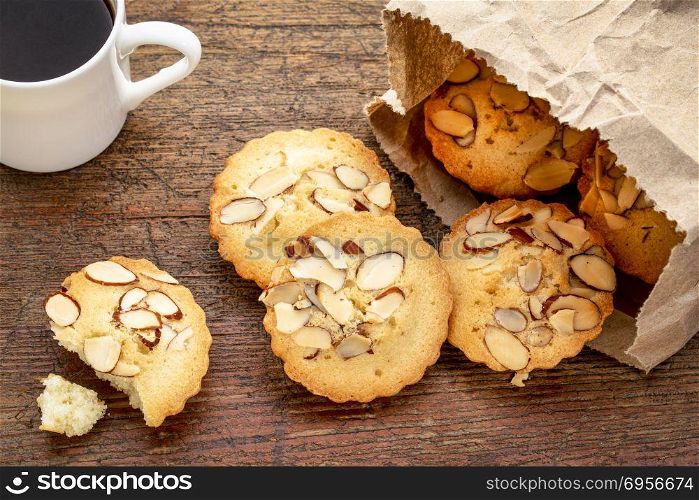 French almond cookies and coffee. a bag of French almond cookies and espresso coffee against weathered wood background