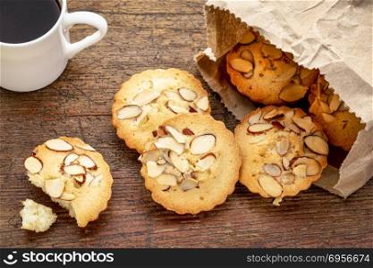 French almond cookies and coffee. a bag of French almond cookies and espresso coffee against weathered wood background