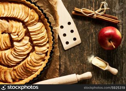 French apple pie and ingredients over rustic background