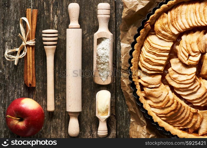 French apple pie and ingredients over rustic background