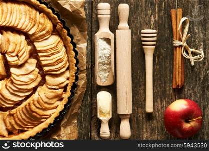 French apple pie and ingredients over rustic background