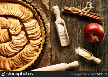 French apple pie and ingredients over rustic background