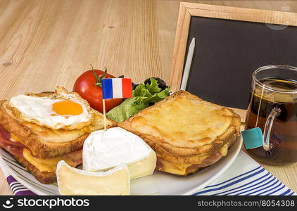 French breakfast and blank chalkboard - Specific french breakfast with melted cheese sandwiches, white cheese with the french flag, salad, cup of tea and a blank chalkboard, on a wooden table.