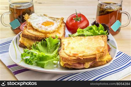 French breakfast for two people - Tasty breakfast for two persons with specific french food, croque madame (with egg) and croque monsieur, seasoned with fresh salad and tea.