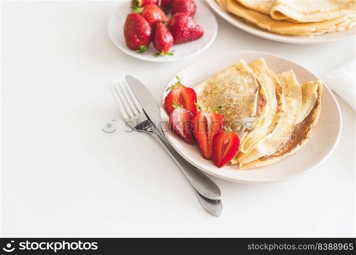 French crepes with chocolate spread and strawberries on white table