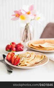 French crepes with chocolate spread and strawberries on white table