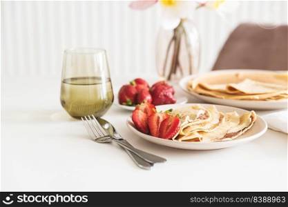 French crepes with chocolate spread and strawberries on white table. Copy space
