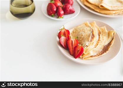 French crepes with chocolate spread and strawberries on white table. Copy space