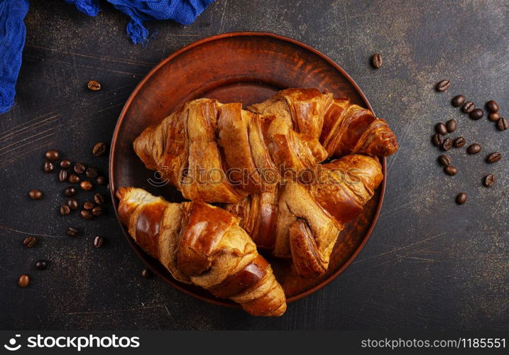 French croissant. Freshly baked croissants with jam on dark stone background.